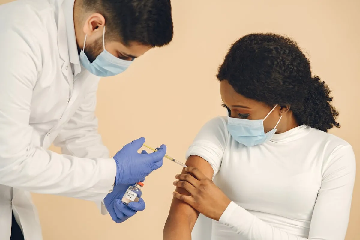 A medical professional giving a vaccine injection to a patient wearing face masks for safety.